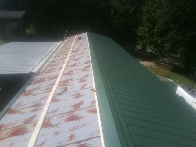 Old rusted panels beside newly installed green metal roofing — Wind Damage Roof Repair by Roofing Brothers in Oak Hill